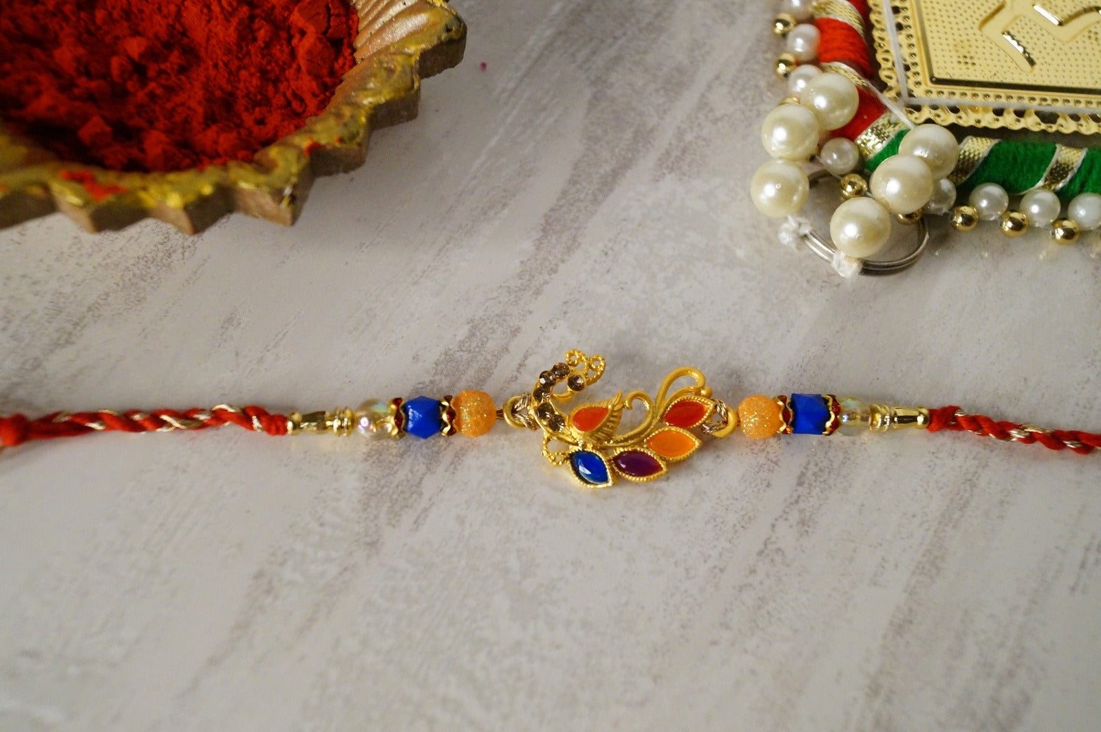 Peaccock Colorful Stone and Gold Brass Thread Rakhi by Kamakhyaa with Brass, Festive Wear, Multicolor, Natural Materials, Natural Threads, Rakhi, Rakhis Ready to Ship, Regular Fit, Upcycled, Zari Threads at Kamakhyaa for sustainable fashion