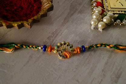 Peacock Stone and Gold Brass Thread Rakhi by Kamakhyaa with Brass, Festive Wear, Jewellery, Multicolor, Natural Materials, Natural Threads, Rakhi, Rakhis Ready to Ship, Regular Fit, Upcycled, Zari Threads at Kamakhyaa for sustainable fashion